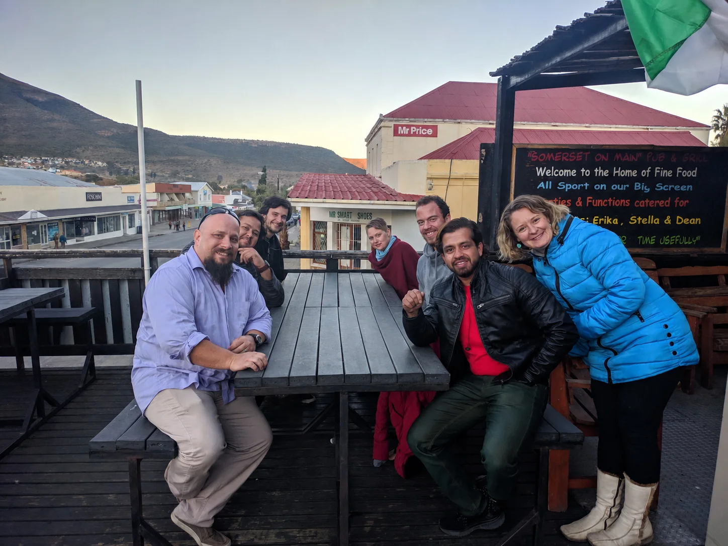 Deepak seated second from right with a group at an outdoor restaurant.
